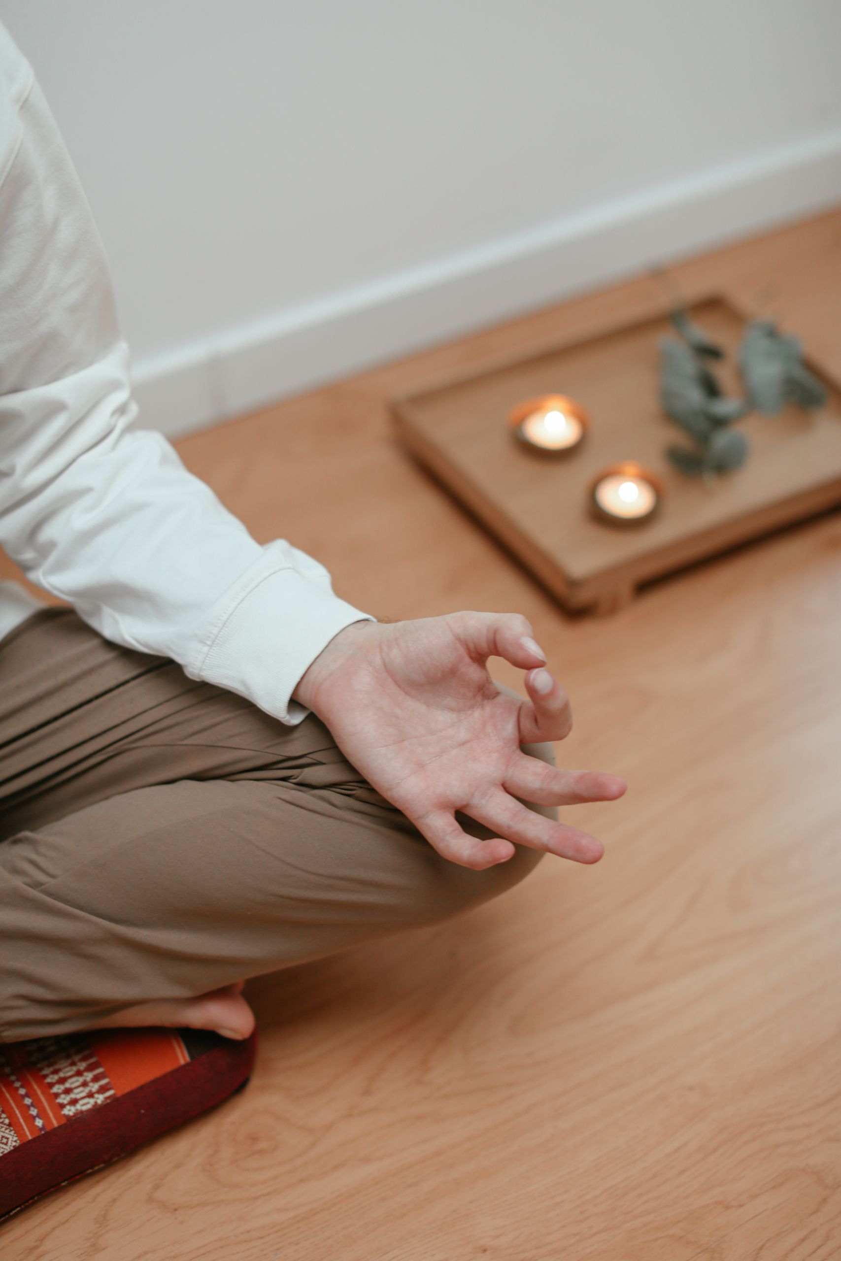 A serene close-up of a person meditating indoors with candles and a peaceful ambiance.